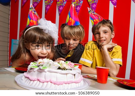 Little girl going to eat cake in her birthday round about her friends