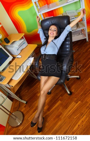 Office portrait of beautiful businesswoman stretching at her workplace