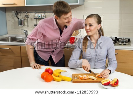 Young woman cutting fruits with her boyfriend on kitchen