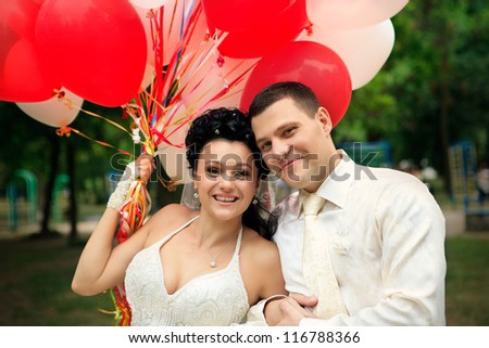 A groom and bride with red and white balloons