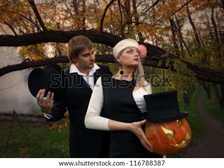 Portrait of a beautiful  vampire couple in medieval costumes with Halloween pumpkin in forest