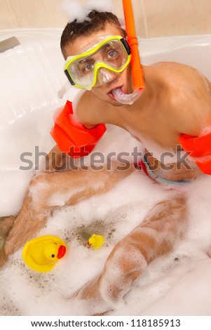 Guy is enjoying a bath in mask with snorkel. Playing with his rubber ducky.