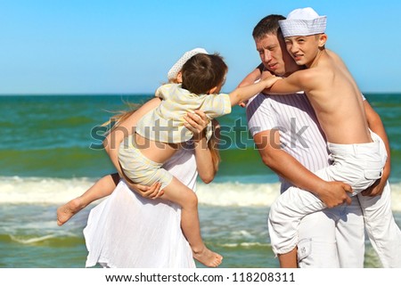 Happy family. Parents holding  sons in theirs arms on beach while on vacation