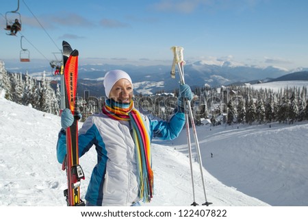 Female skier holding ski; blue jacket; horizontal orientation