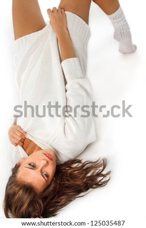Attractive girl in white wool sweater lying over white