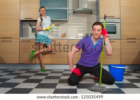 Young man cleaning floor with his girlfriend at kitchen
