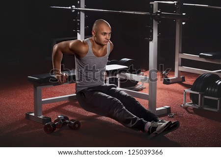 Muscular back of young bodybuilder training in fitness club