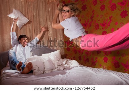 Happy girlfriend flying on bed to her sweetheart at home
