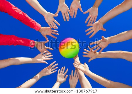 Several hands reaching out together in a circle for volley ball against blue sky