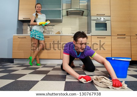 Young man cleaning floor and looking at her girlfriend