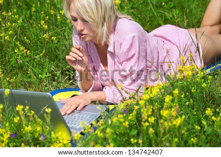 Woman with laptop sitting on field