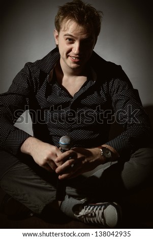 Young handsome guy singing and sitting on floor