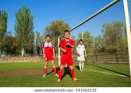 Little Boys playing soccer on the sports field next to goal