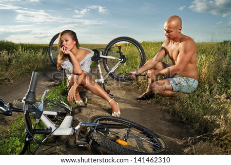 Bicycle has flat tyre and man helps his girlfriend pump it up
