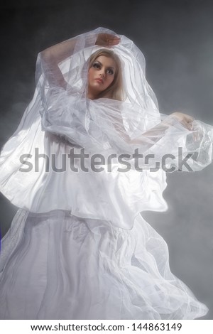 Sexy witch dressed up in white dress covered in smoke