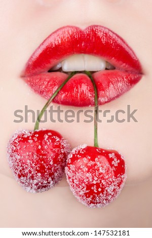 Young woman\'s mouth with red cherries covered with sugar