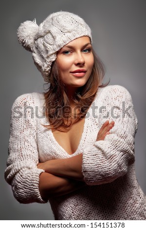 Young attractive girl in white wool and cap over darkness