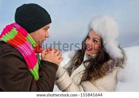 Bright picture of family couple in a winter clothes. He warms her hands
