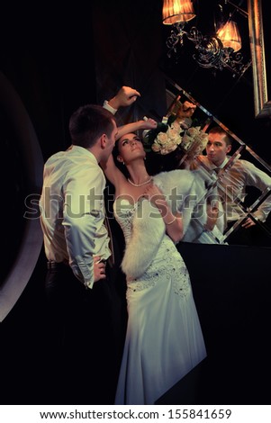 Wedding shot of bride and groom kissing next to mirror