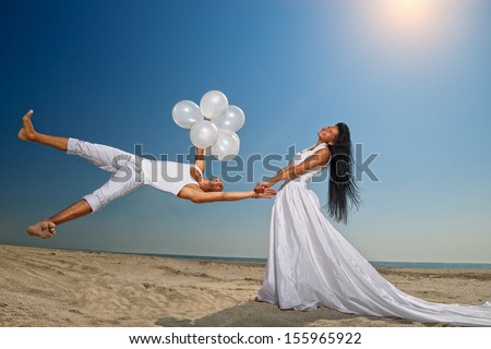 Happy groom flying to his sweetheart on the beach