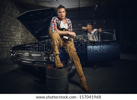 Guitarists at a garage next to the retro car in smoke