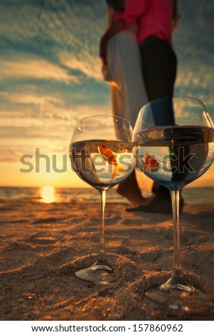 Reflection of holding bride and groom in wine glasses with golden fishes