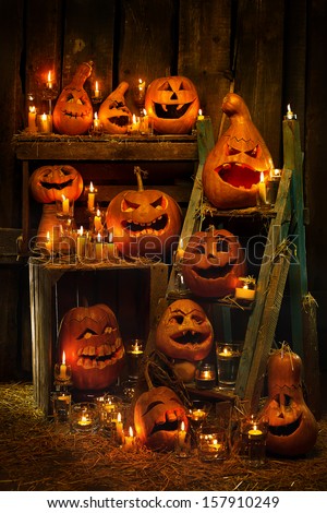 Scary Jack O Lantern Halloween pumpkins against wooden wall in darkness