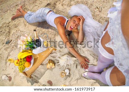 Romantic boyfriend kissing bride`s legs on the beach (I\'ll throw everything at your feet)