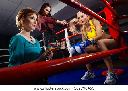 Boxing Woman in box gloves sitting on ring and surrounded by Visagiste and Hairdresser