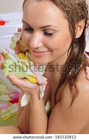 Sensual woman relaxing in bathtub with foam soap sud and rose petal