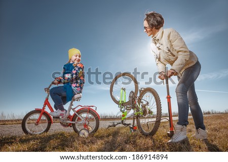 Bicycle has flat tyre and  mother helps her daughter pump it up