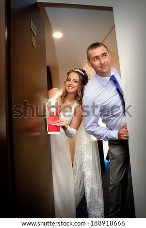 The newlyweds closing the door in hotel. Just married do not disturb sign