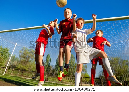 Little Boys playing soccer on the sports field next to goal