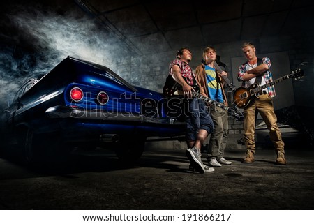 Guitarists at a garage next to the retro car in smoke