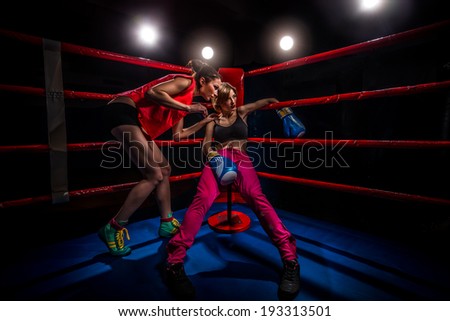 Boxing Woman in box gloves sitting on ring and surrounded by trainer