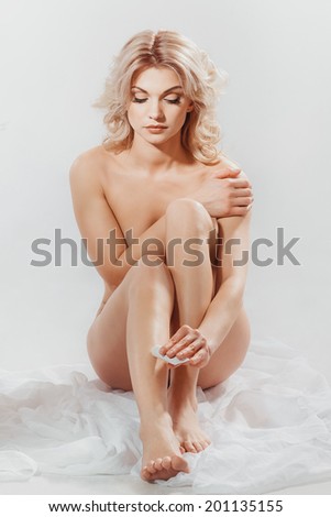Woman applying moisturizer cream on the legs over white background