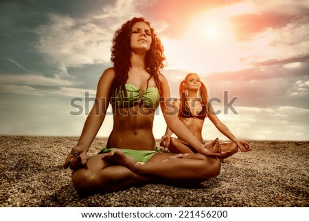 Young women practicing morning meditation in nature at the beach