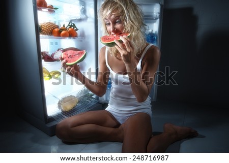 Diet. Hungry Young Woman near the Refrigerator with healthy food. Fruits in a Fridge