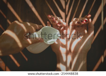 Essential oil in jug pouring on female hands in spa
