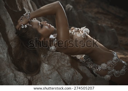 Beautiful woman in shells accessories lying on the beach