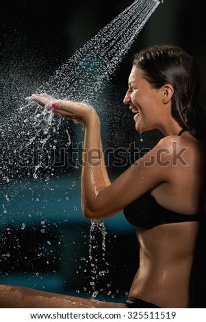 Young sensual woman taking a shower outdoors in bikini