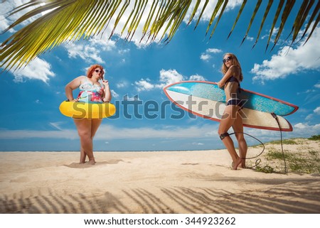 Beautiful young fat woman and skinny girl on the summer beach