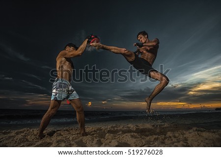 Strong boxer doing back leg high kick during kickboxing exercise with trainer at sunset