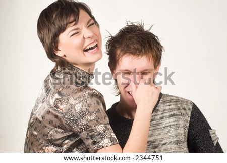 Two young beautiful people joking: girl holding nose of her boyfriend \
