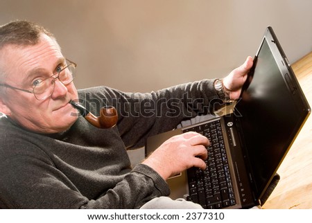 old man working on the laptop computer, smoking pipe