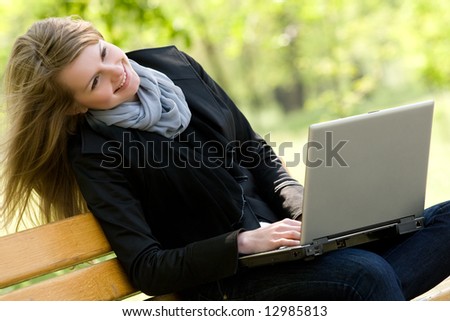 Joyful young blond with laptop in the park