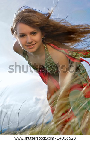 Natural blond girl at green meadow with hair flying