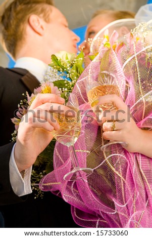 Beautiful bride and groom holding champagne and flowers