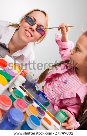 Adorable little girl painting mother's glasses