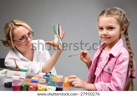 Little girl playing with mom, painting her fingers